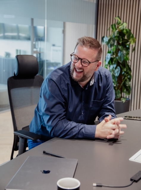 Man with glasses laughing in conference room