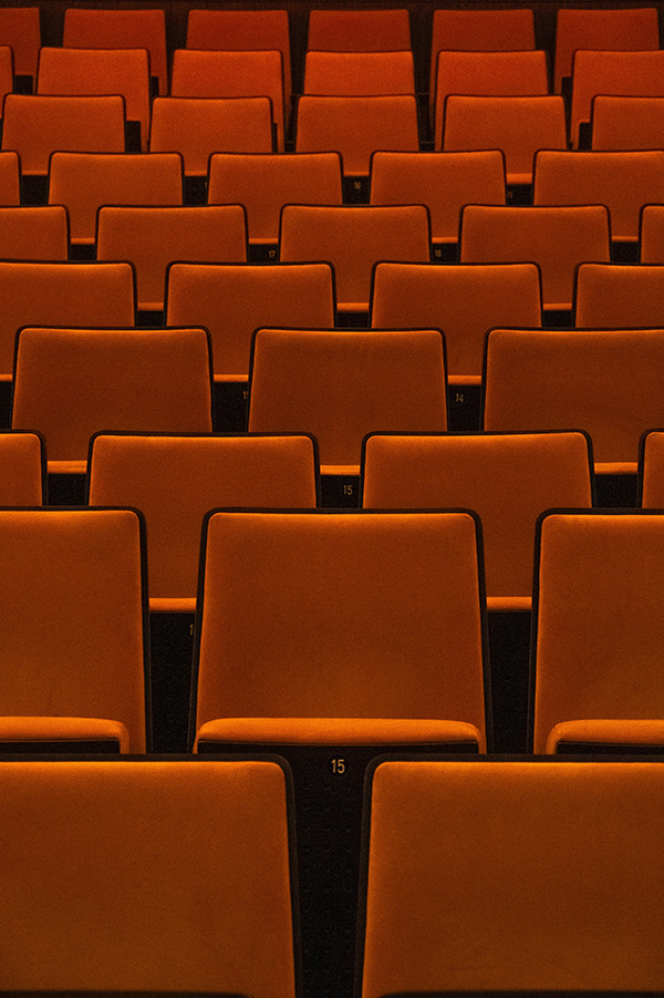 Disposición geométrica y simétrica de muchos asientos rojos en un teatro